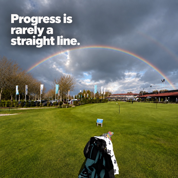 A rainbow over a golf course with the words Progress is rarely a straight line